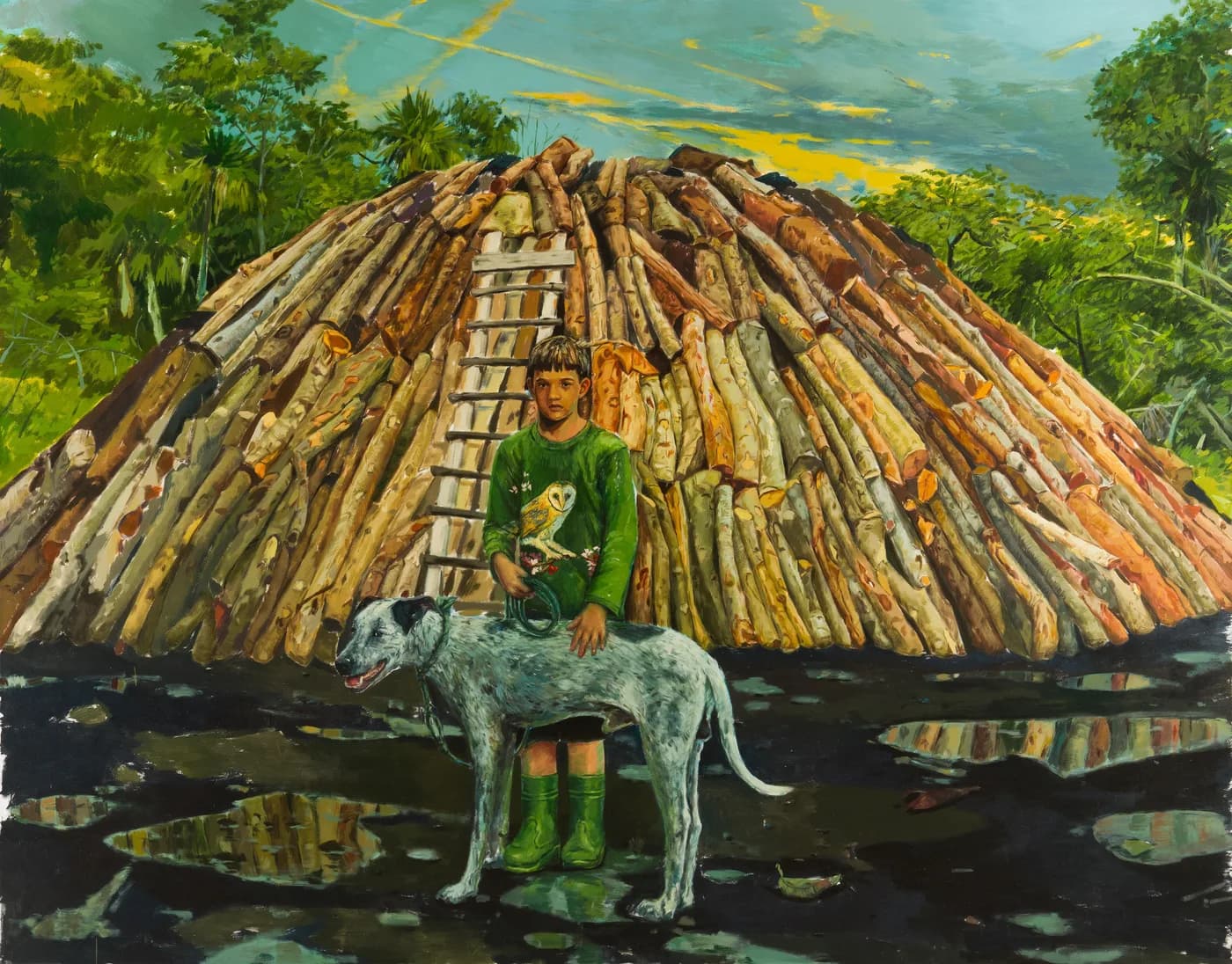 Un niño con jersey verde de búho y botas de agua verdes, con la mano sobre el lomo de un perro moteado, posa ante un enorme horno de carbón de troncos apilados, en un suelo negro con charcos que reflejan la leña.