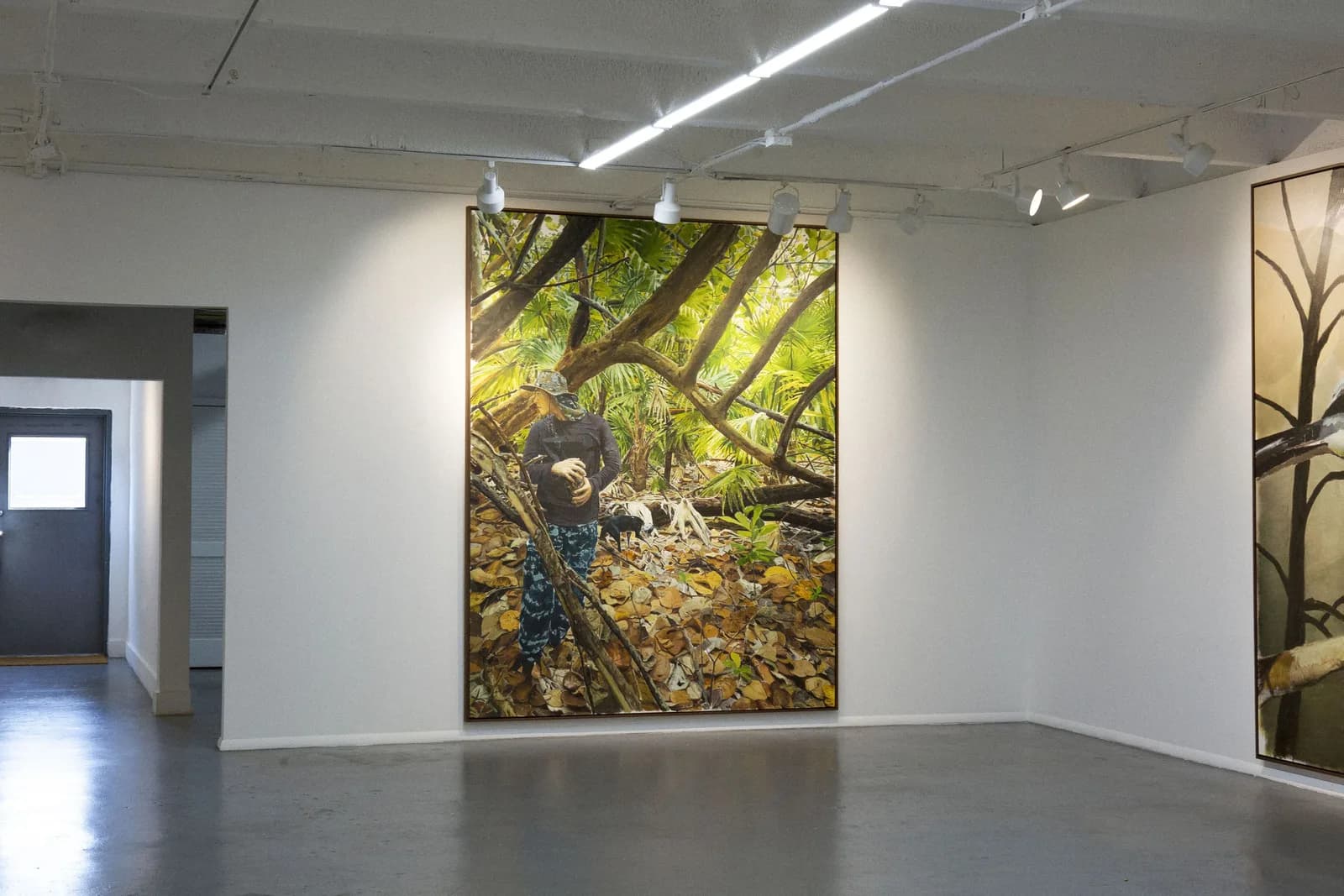 Pintura vertical de una figura agachada en un bosque, junto a una puerta abierta de la sala.
